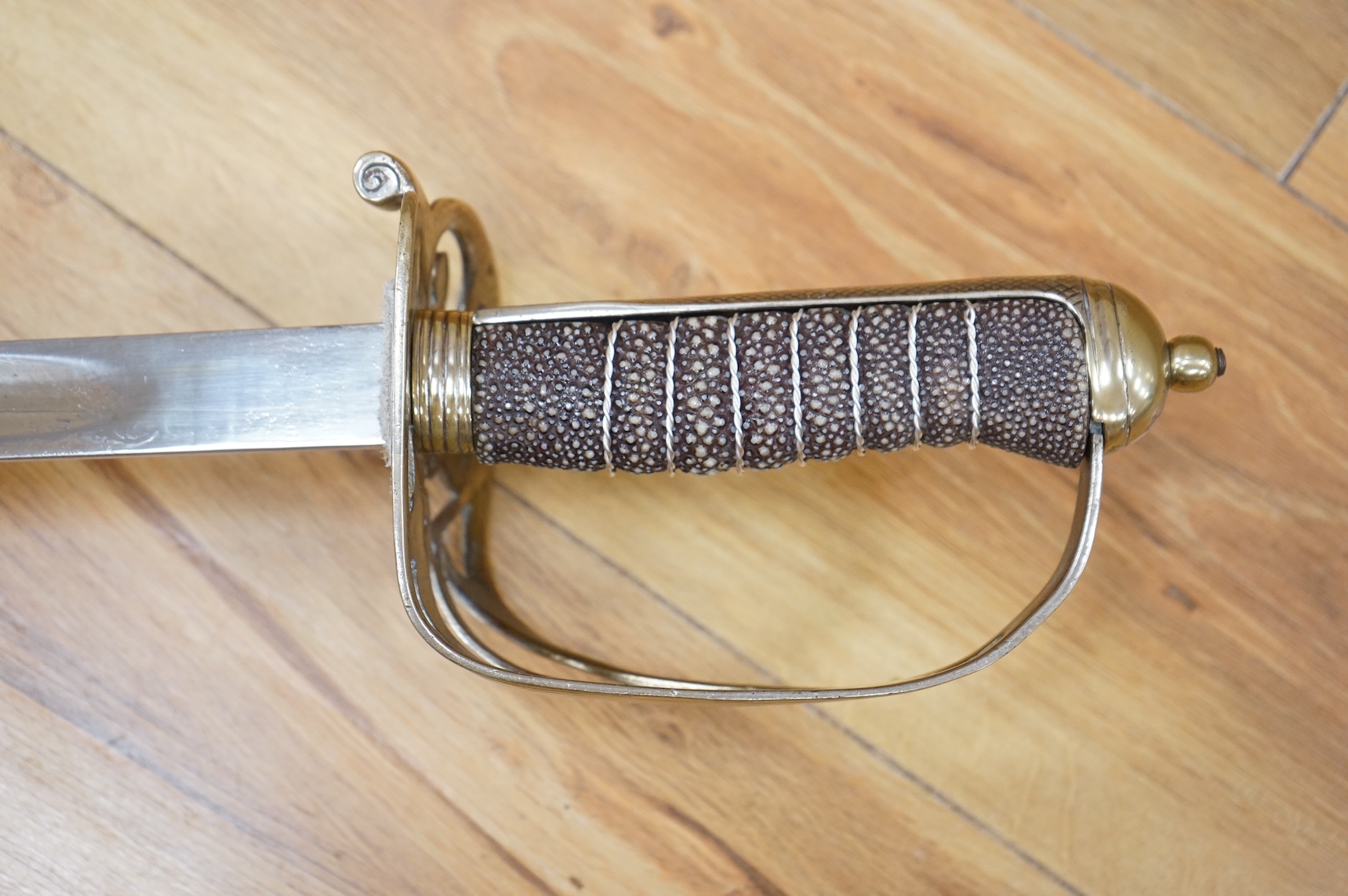 A post 1902, 1827 pattern Rifle Brigade officer’s dress sword, with regulation blade with traces of edge decoration, regulation nickel guard with crown strung bugle and wire bound fish skin covered grip, in its steel sca